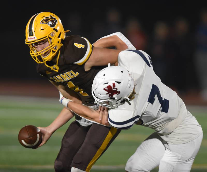 Joe Lewnard/jlewnard@dailyherald.com
Carmel quarterback Johnny Webber, left, gets sacked by St. Viator’s Michael Tauscher during Friday’s game in Mundelein.