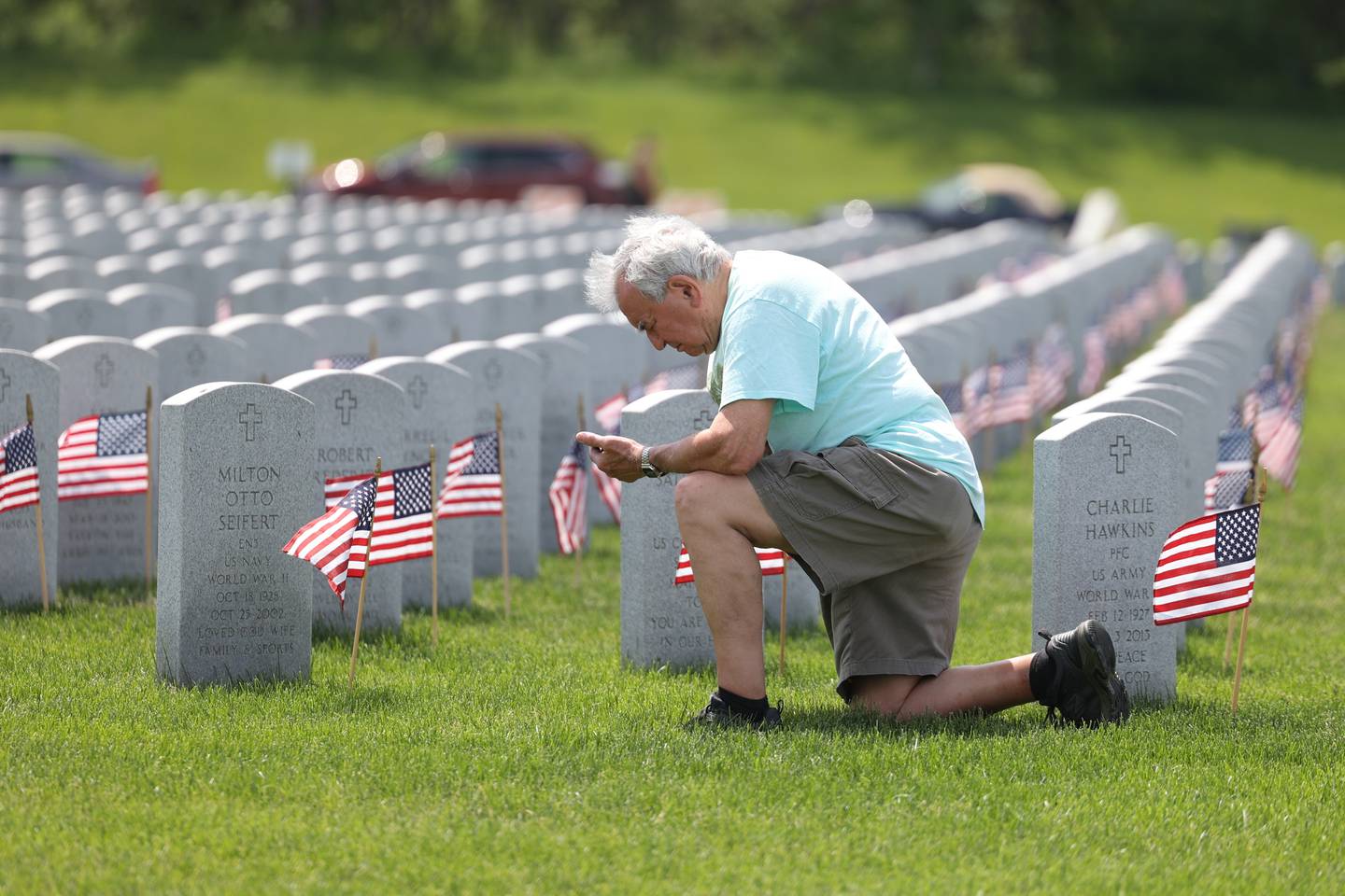A man kneels at the grave of a friend at the 23rd Annual Memorial Day Ceremony at Abraham Lincoln National Cemetery. Monday, May 220, 2022 in Elwood.