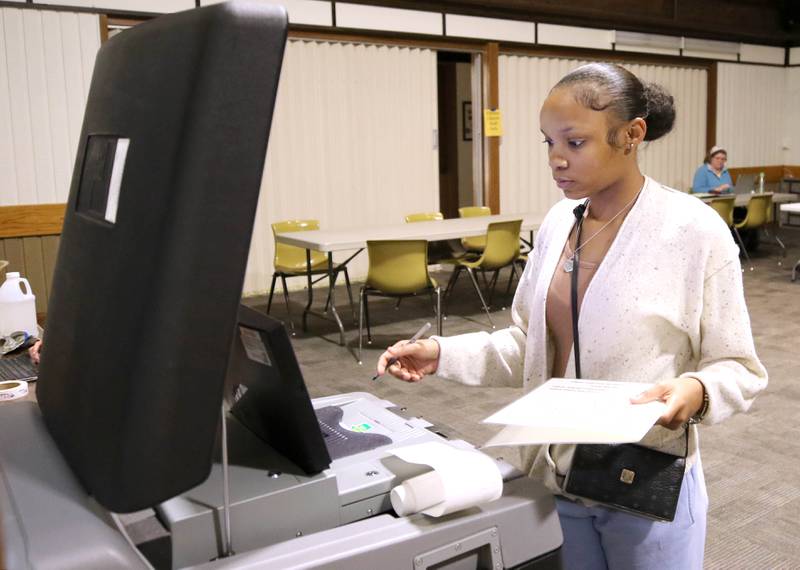 Arianna Chandler, a senior at Northern Illinois University, feeds her ballot into the collection machine on Election Day, Tuesday, Nov. 8, 2022, at the polling place in Westminster Presbyterian Church in DeKalb.