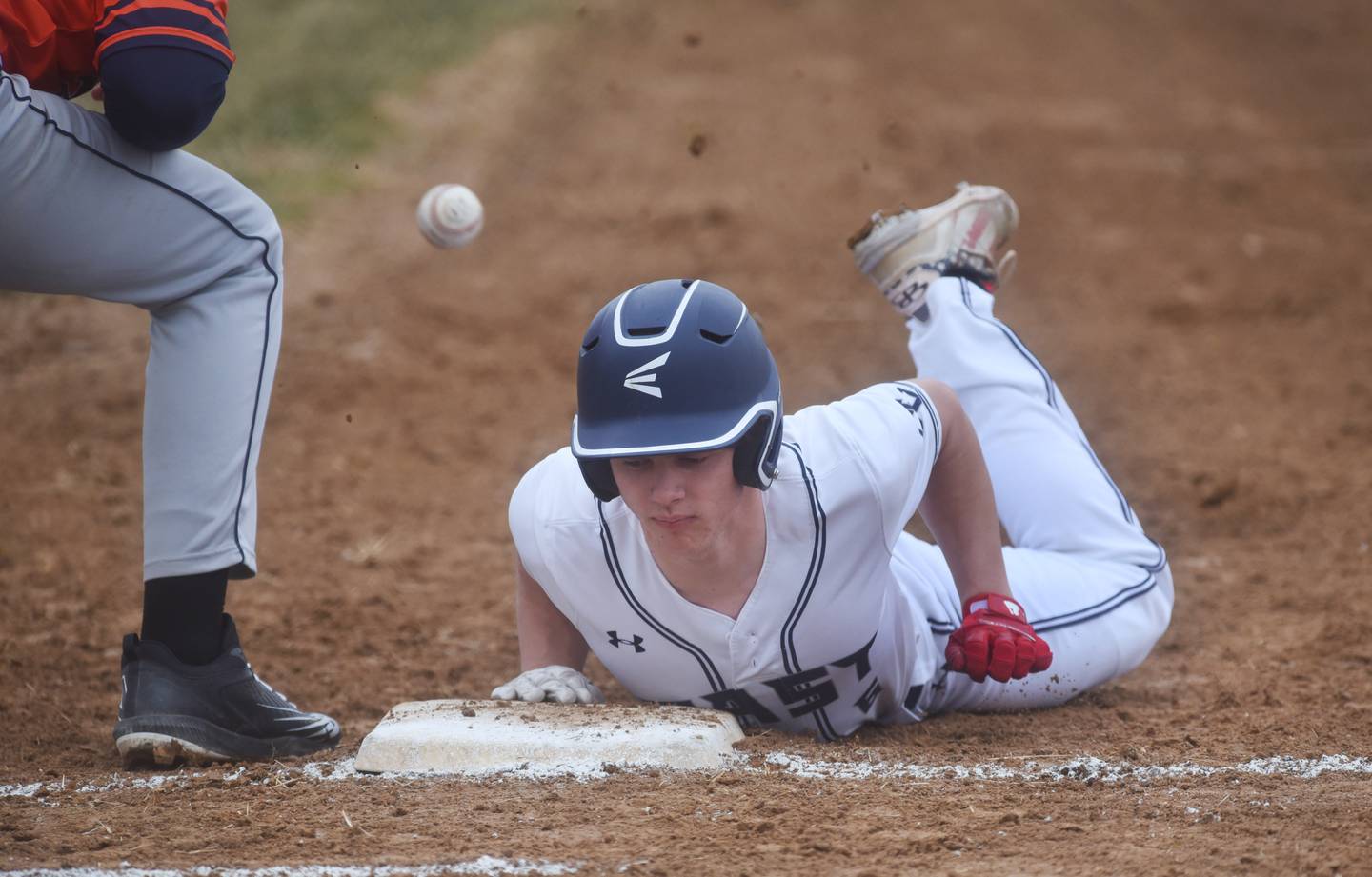 Oswego East's Liam Mitchell slides safely back to first base during Wednesday's baseball game against Naperville North in Naperville.
