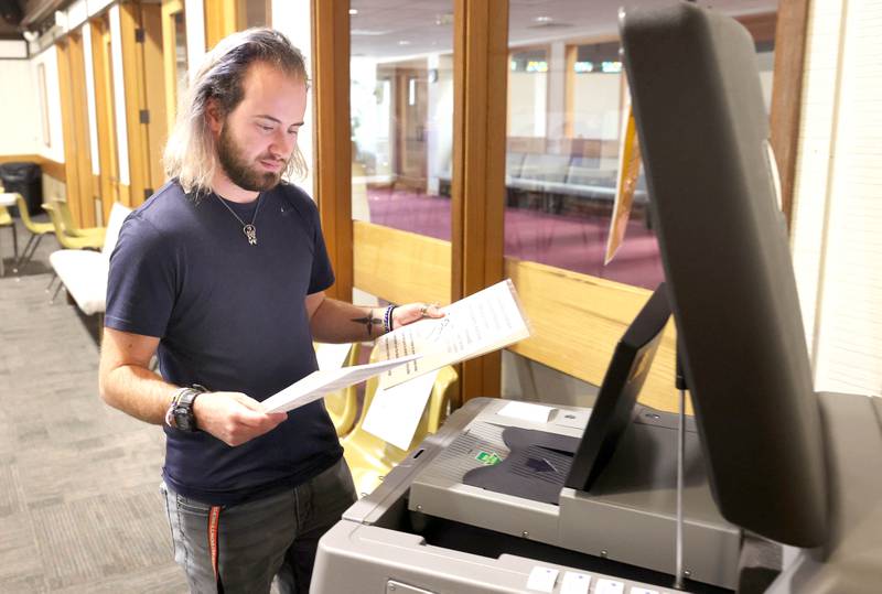 Northern Illinois University senior Dallas Douglass, from DeKalb, checks his ballot before feeding it into the collection machine Tuesday, June 28, 2022, at the polling place in Westminster Presbyterian Church in DeKalb.