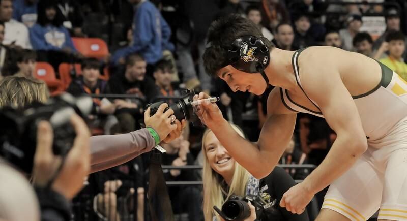 Fremd’s Evan Gosz signs an autograph on a glass cover on a camera after defeating Marmion’s Zach Stewart in the Class 3A 144-pound final at the IHSA boys state wrestling championships at the State Farm Center in Champaign on Saturday, Feb. 22, 2025.