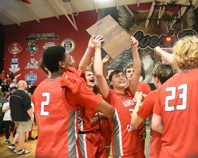Aurora Christian's Jacob Baumann (22) celebrates with his teammates as he holds up the regional title plaque as they defeated Yorkville Christian on Friday Feb. 28, 2025, held at Indian Creek High School.