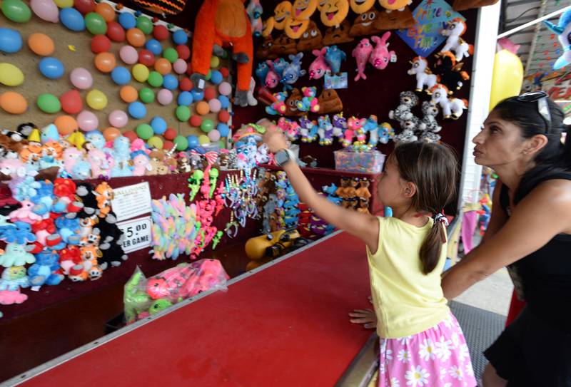 Nikki Van Beveran of Western Springs watches while her daughter Annika plays the balloon dart game at the La Grange Summerfest Saturday Aug 6, 2022.