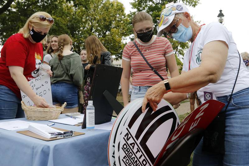 McHenry County board member Paula Yensen, also the president of the McHenry County National Organization for Women, right, helps Logan West, 16, of Cary, pick out a sign to use during a rally for abortion rights on the historic Woodstock Square on Saturday, Oct. 2, 2021, in Woodstock.