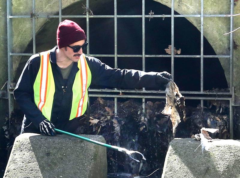 Aaron Schwab, from DeKalb, cleans trash and debris from a storm drain pipe Monday, April 22, 2024, during an Earth Day Clean Up event at Hopkins Park in DeKalb.