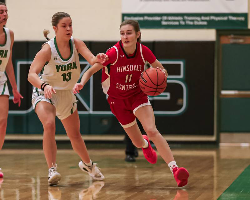 Hinsdale Central's Julia Sherpitis (11) drives past the defense of York's Mia Pretzie (13) during basketball game between Hinsdale Central at York. Dec 8, 2023.
