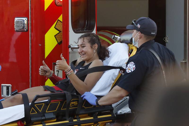 Huntley's Sophie Amin gives a thumbs up to the crowd as she is loaded into an ambulance after a bad fall in the100 meter hurdles Friday, May 10, 2023, during the IHSA Class 3A Huntley Girls Track and Field Sectional at Huntley High School.