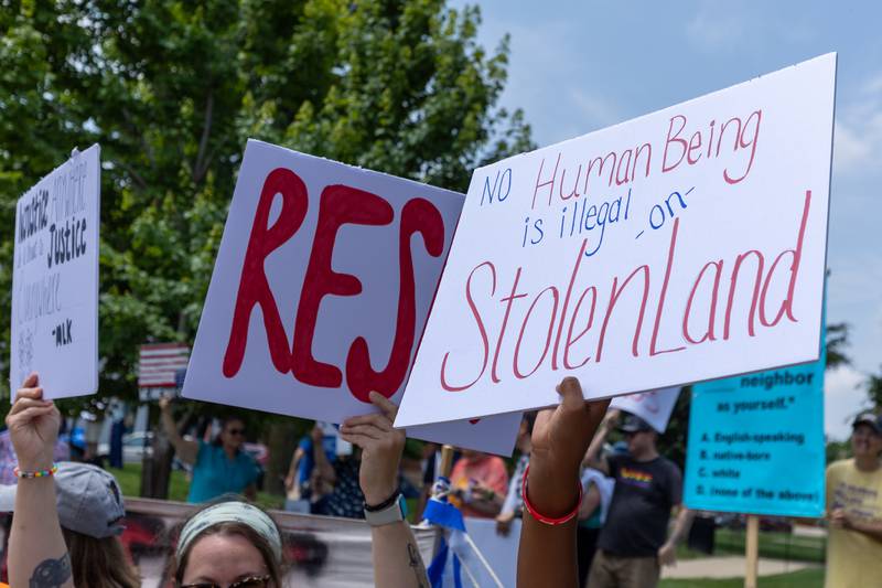 (right) Sign that reads “ no human being is illegal on stolen land” is held at the “No Kings” protest on Saturday, June 14, 2025 at Rotary Park in Princeton.