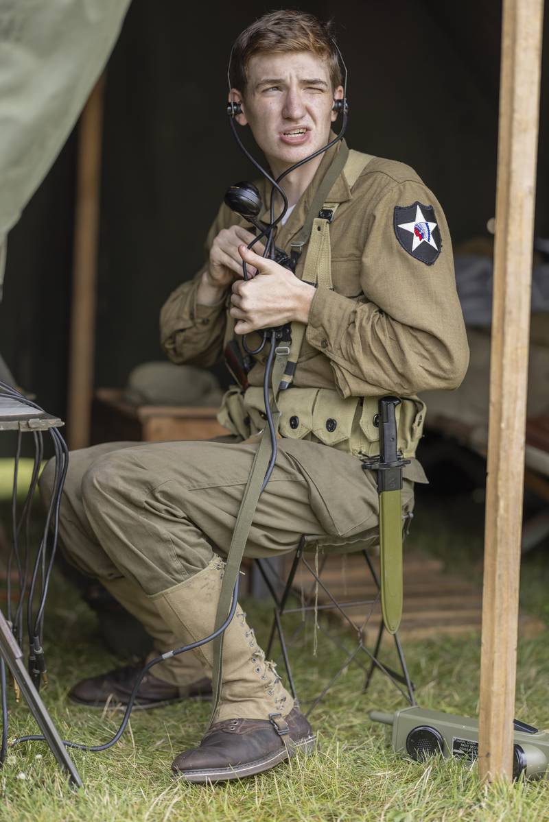 Tyler Phifer, a signaler, receives a radio confirmation that enemy soldiers have been spotted in the region in a simulated battle Sunday, July 14, 2024, during the Ottawa Military Show in rural Ottawa.