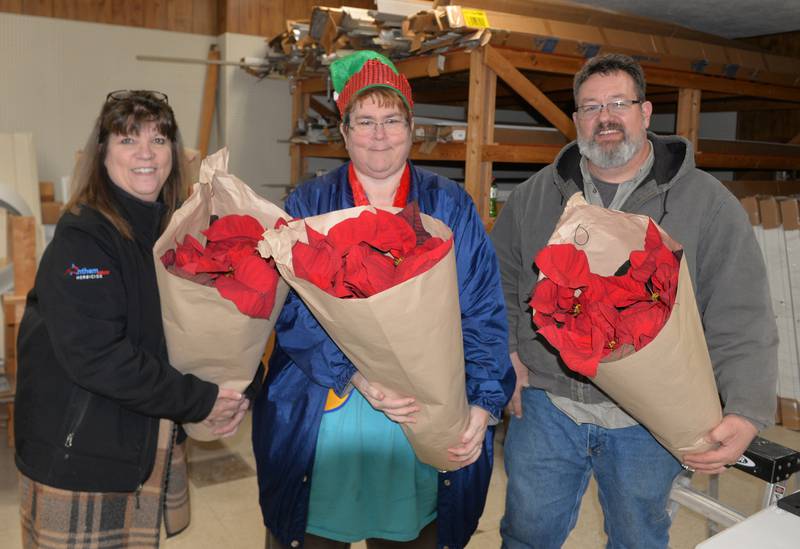 The Forreston Lions Club sold poinsettias during Christmas in the Country on Friday, Dec. 1, 2023. Missy Clark, Michelle Jacobs, and Dave Vinnedge hold three of the plants that cost $15 each during the fundraising event.