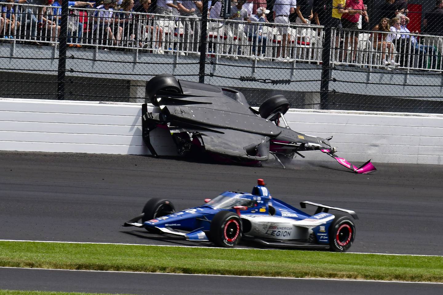 The car driven by Kyle Kirkwood, top, flips over after a crash in the second turn during the Indianapolis 500, Sunday, May 28, 2023, at Indianapolis Motor Speedway.