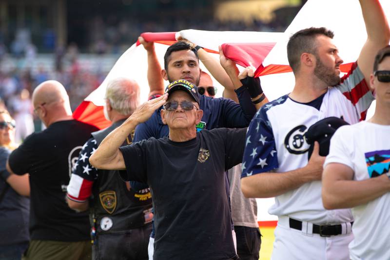 Vietnam Combat Veteran, Al Scott of Aurora stands and salutes while holding the American Flag on the Kane County Cougar's Military Appreciation Night on Saturday, July 2, 2022