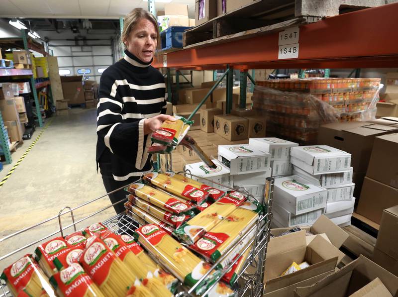 Rooted for Good Executive Director Heather Edwards fills a cart with pasta Thursday, Oct. 30, 2025, at the facility in DeKalb. The food pantry is preparing for the potential impact of SNAP benefits being cut off due to the government shut down and the large influx of new patrons it may bring.