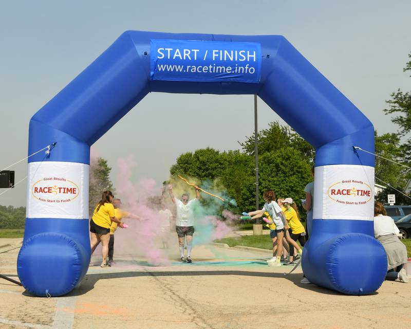 Mary Beth Nelms of Glen Ellyn celebrates as she gets sprayed by color powder before crossing the finish line on Saturday, June 7, 2025, during the CASA DeKalb County 5K Color Run held at the Sycamore Middle School.