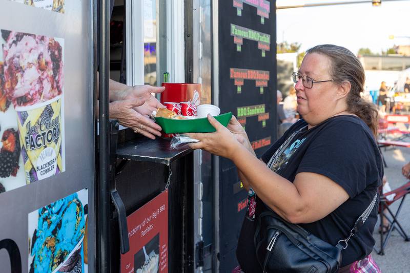 Regina Jorgensen is handed beef roll stuffed pizza from Lil Bella's Pizza trailer at the BBQ & Blues Fest on Saturday, Sept. 12, 2025 on First Street in La Salle.