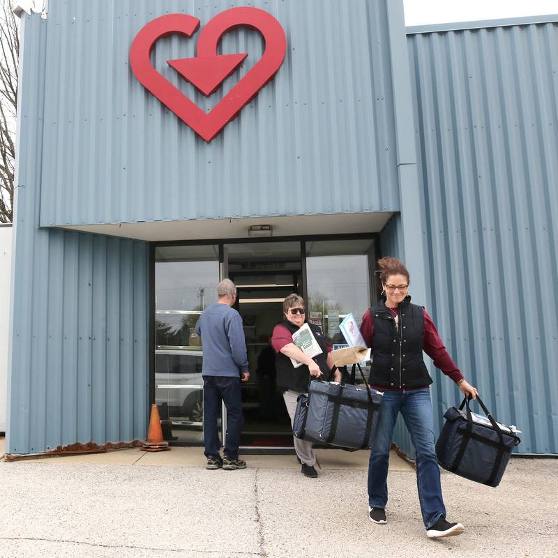 Volunteers Stephanie Barring (left) and Chris Sauter, both from DeKalb, pick up a Meals on Wheels delivery to distribute Tuesday, April 23, 2024, at the Voluntary Action Center in Sycamore. VAC is celebrating its 50th anniversary this year.