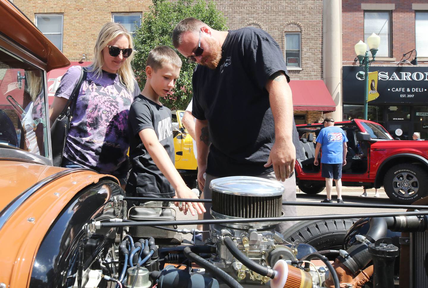 Brittney Wallin, (left) Carter Robinson, 9, and his dad Alex Robinson (right) check out one of the cars on State Street during the Fizz Ehrler Memorial Turning Back Time Car Show Sunday, July 30, 2023, in downtown Sycamore.