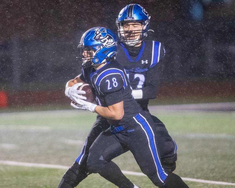 St. Charles North's Jesse Pardon hands the ball off to Carsen Durante against Carmel at the Class 7A Second Round playoff game on Saturday, Nov.8,2025 in St. Charles.