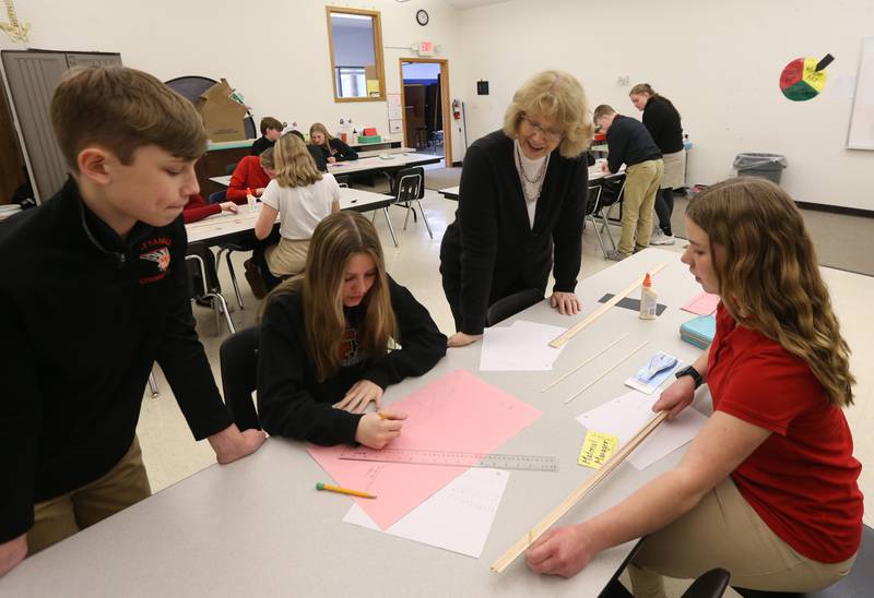 Lynn Quick helps students  with building a bridge out of wood on Wednesday, March 22, 2023, at Holy Family School in Oglesby.