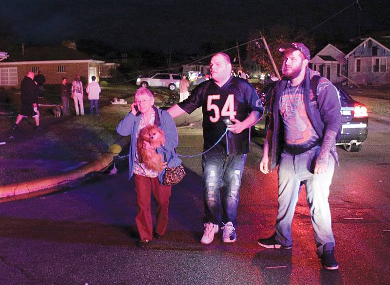 Naplate residents Jeremy Gossett (right) and Mathew McBee (center) help escort a woman and her dog to a fire truck following a tornado on Tuesday, Feb 28, 2017 in Naplate.