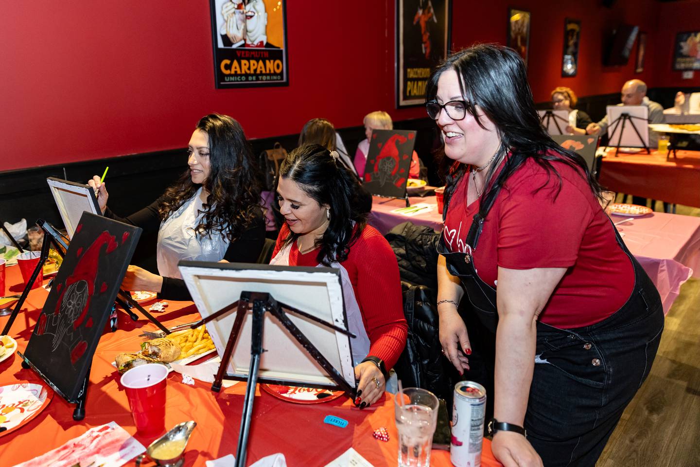 Plainfield resident Elisa Villalobos and Brenda Gonzalez, of Joliet, get tips from Divine Design Paint Studio owner and artist, Annie Flint, during the paint party at Papa Joe's in Lockport on Feb. 6, 2025.