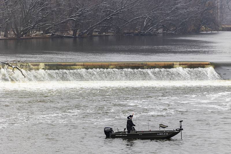 With snow speckled trees on the distant island, a fisherman casts below the dam in Dixon on Tuesday, Nov. 15, 2022.