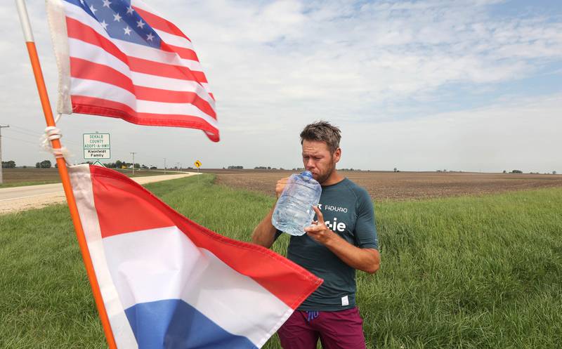 Tom Boerman, from the Netherlands, has a drink and eats lunch during a break from walking Tuesday, May 24, 2022, at the intersection of Old State and Ault Roads near Kirkland. Boerman, who stopped for the nightat a home in DeKalb, is on a quest to walk around the world while raising money for schools in Nepal that were hit hard by the 2015 earthquake in the region.