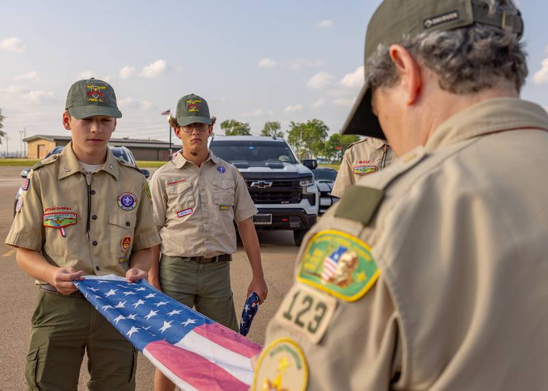Melissa Olivero, Scoutmaster of Troop 123 instructs scouts Gabriel Bunch (left) and Dominic Morgan (right) the proper method to folding a flag prior to the flag retirement ceremony on June 14, 2025 in Peru.