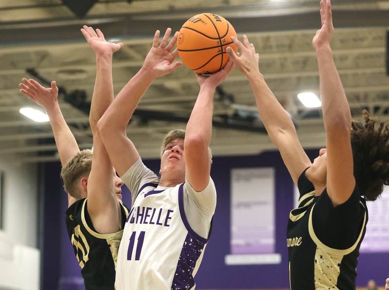 Rochelle's Brody Bruns goes to the basket between a pair of Sycamore defenders Friday, Dec. 5, 2025, during their game at Rochelle High School.