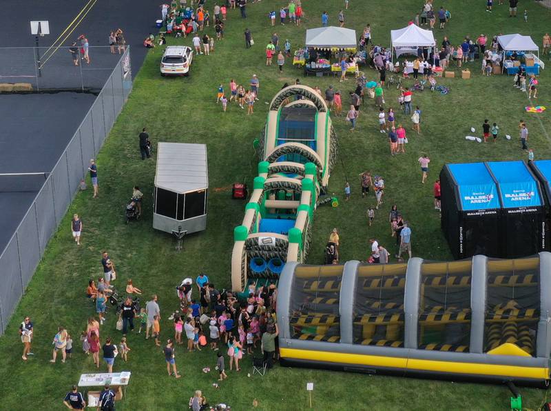 Kids wait their turn for a huge bounce house obstacle course during the National Night Out event on Tuesday, Aug. 1, 2023 at Kirby Park in Spring Valley.