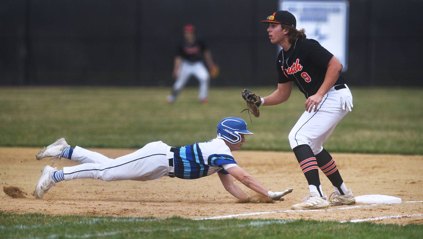 St. Charles North's Christopher Graziano slides safely back to first base on a pickoff attempt as Wheaton Warrenville South's Casey Farrell (9) waits for the throw during Tuesday's baseball game in St. Charles.