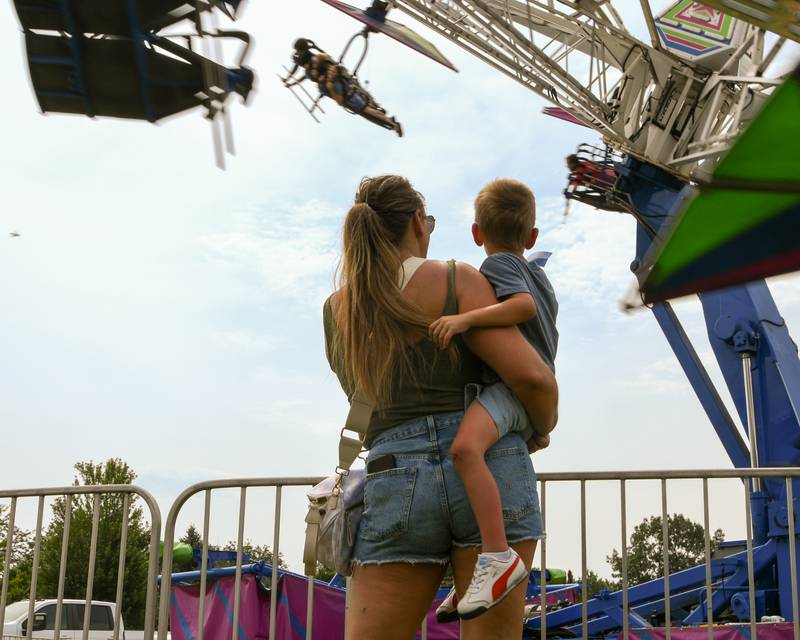 Kristina Yockey holds her 4 yr old son Briggs as they watch family enjoy the Zero Gravity ride during the Elburn days on Saturday Aug 16, 2025, held at Lions Park in Elburn.