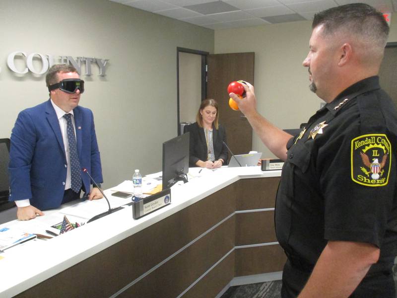 Kendall County Board Chairman Scott Gryder cannot distinguish between the three colored billiard balls being held up by Kendall County Undersheriff Bobby Richardson, while wearing goggles simulating the effects of marijuana, on Sept. 20, 2022.