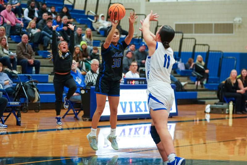 St. Charles North's Lelanie Posada (30) shoots a 3-pointer against Geneva’s Heidi Clesen (11) during a game at Geneva High School on Thursday, Dec. 4, 2025.