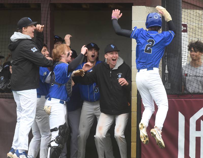 St. Francis's Jake Smagacz (2) scored a run and jumps into the dugout where teammates are waiting to celebrate during Tuesday’s baseball game against Wheaton Academy in West Chicago.