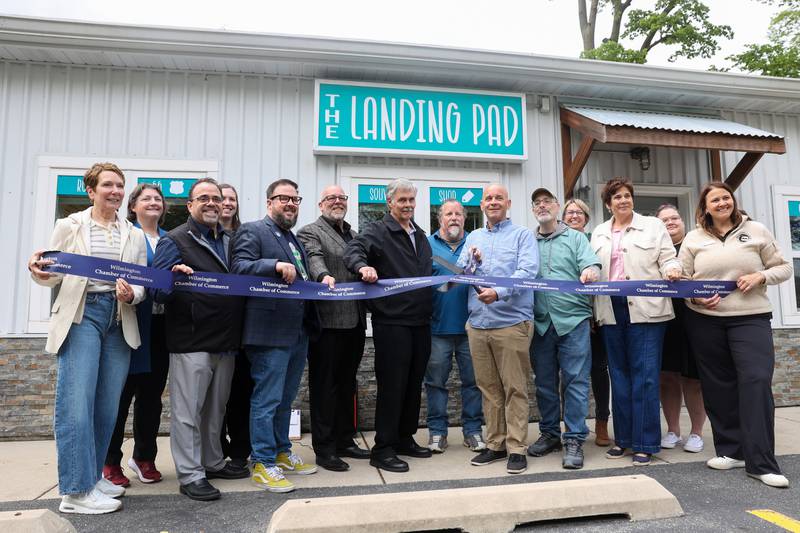 Officials from the Joliet Area Historical Museum, Heritage Corridor Destinations, the Wilmington Park District and the city of Wilmington, including Mayor Ben Dietz, right of center, participate in a ribbon cutting with the Wilmington Chamber of Commerce during The Landing Pad Souvenir Shop's grand opening at Wilmington's South Island Park on Thursday, May 22, 2025.