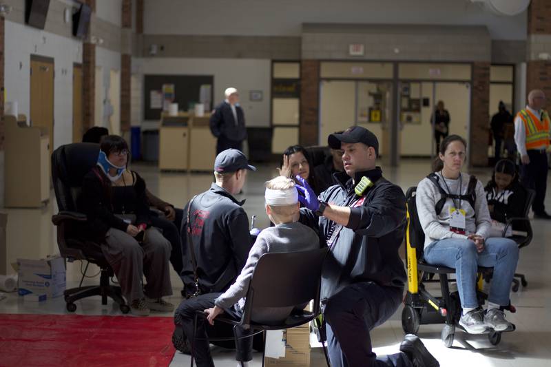 Paramedics providing medical care for student actors inside Joliet West High School on Tuesday, March 25, 2025, for a staged emergency drill simulating the aftermath of a gas explosion. The actors near the red mat are considered the most critically injured patients who must be treated first as part of the exercise.