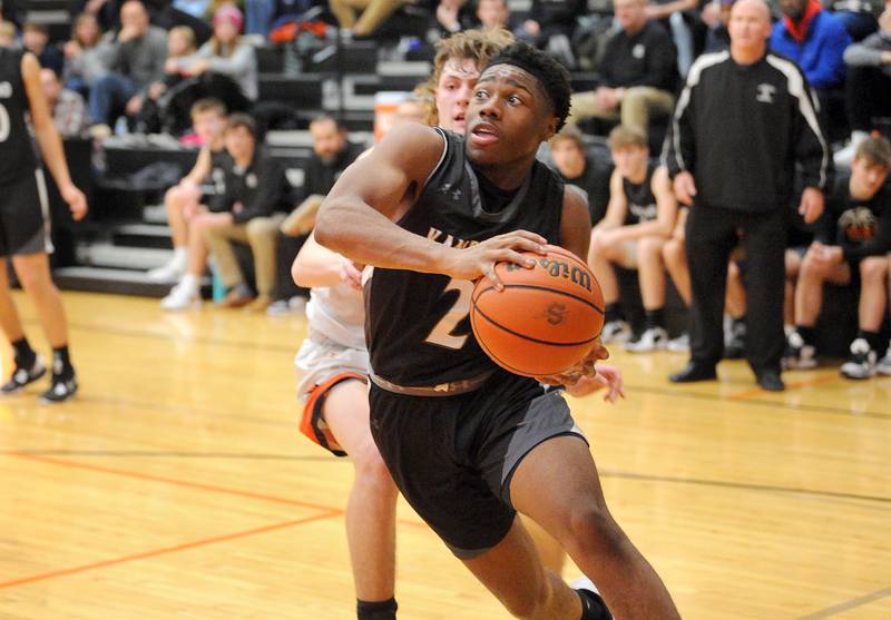 Kaneland's Gevon Grant (2) drives past Sandwich defender Austin Marks during a boys' basketball game at Sandwich High School on Friday, Jan. 13, 2023.