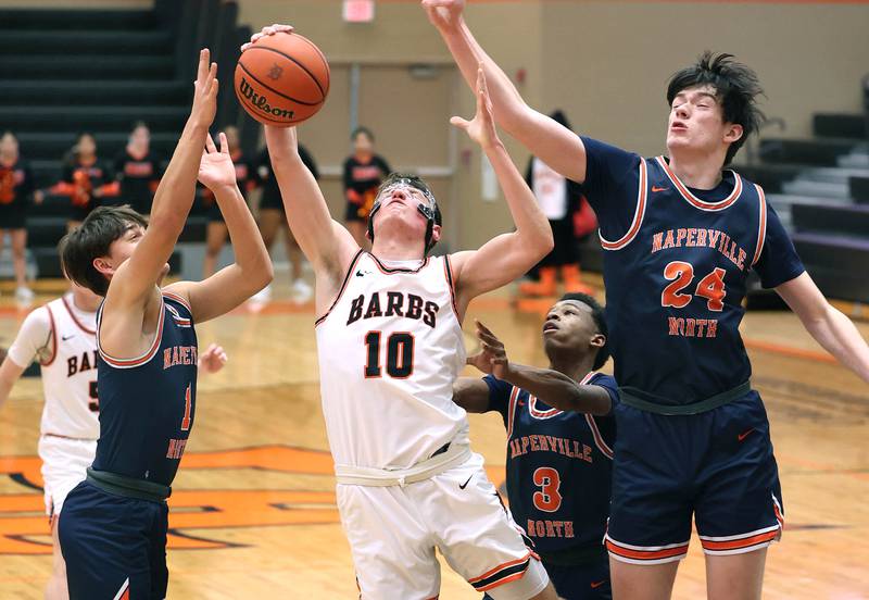 DeKalb's Eric Rosenow grabs a rebound between Naperville North's Cole Arl (left) and Charles Farrell during their game Monday, Jan. 30, 2023, at DeKalb High School.