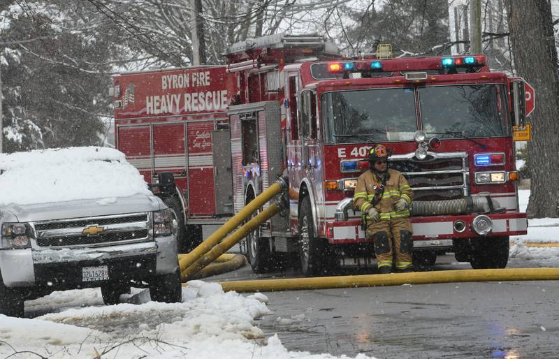 A Byron firefighter rests on the bumper of a fire engine after battling a fire at 115 W. Third Street Saturday morning. One woman was declared dead after being found outside the home after a power line fell on the house causing to become "electrified," a fire official said.