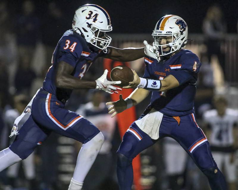 Oswego's Ammar Banire (34) takes the handoff during football game between Oswego East at Oswego Friday, Oct 17, 2025 in Oswego.