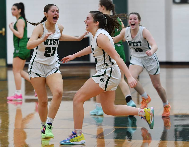 Glenbard West's Makenna Yeager (middle) and teammates Mya Austin (23) and Julia Benjamin (right) celebrate after Yeager scored the winning basket ending a game against York on Jan. 22, 2024 at Glenbard West High School in Glen Ellyn.