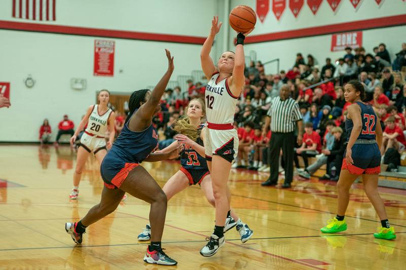 Yorkville's Katlyn Schraeder (12) shoots the ball in the post against Oswego’s Journey Davis (5) and Ashley Cook (33) during the 13th annual Hoops 4 Hope Communities vs. Cancer basketball event at Yorkville High School on Saturday, Jan 28, 2023.
