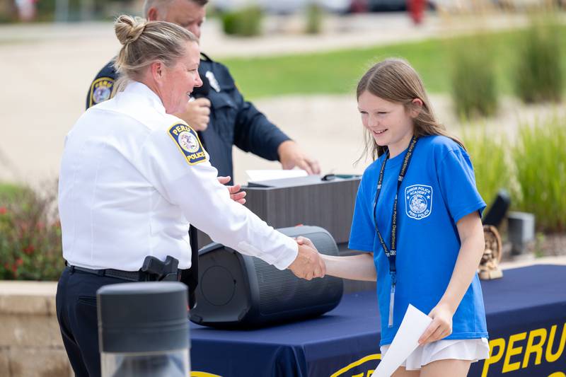 (right) Chief Sarah Raymond shakes hand of graduate Kinley Goode at the first annual Juvenile Police Academy graduation ceremony on Friday, July 25, 2025 at the Peru Police Department in Peru.