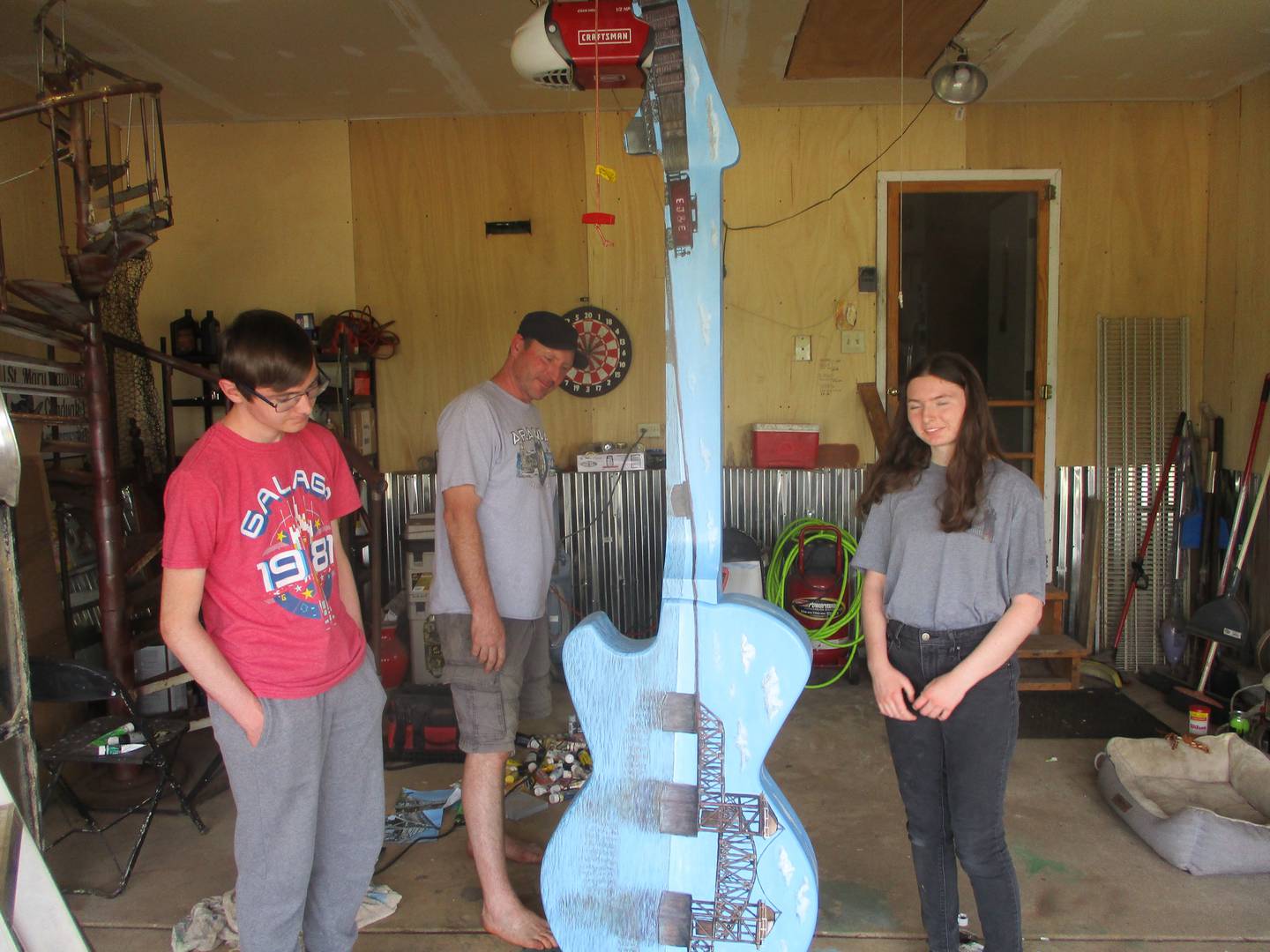 The Benedicks (from left), Jonah, Jeff and Sofia, inspect the guitar they painted for the Ready to Rock street exhibit in Joliet. One side of the guitar shows the railroad bridge that crosses the Des Plaines River in Joliet. May 27,2023.