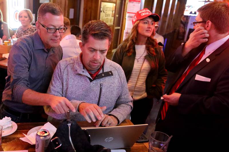 Mike Buehler, from left, looks over results with Mike Shorten, as Tracie Von Bergen talks with Tyler Wilke during an election night watch party for local republicans at Niko's Red Mill Tavern on Tuesday, Nov. 3, 2020 in Woodstock.