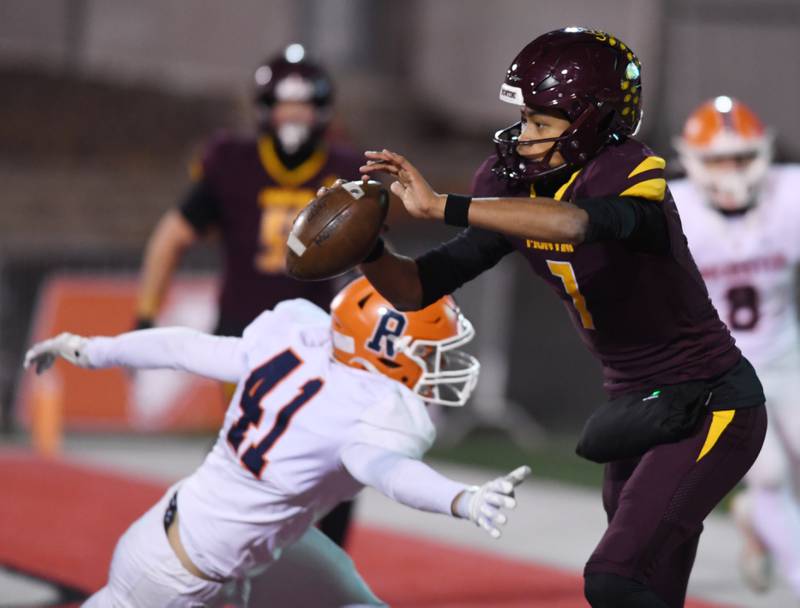 Montini quarterback Israel Abrams dodges Rochester's Parker Seifert and avoids getting sacked on what would have been a safety during the IHSA Class 4A championship game on Friday, Nov. 28, 2025 in Normal.