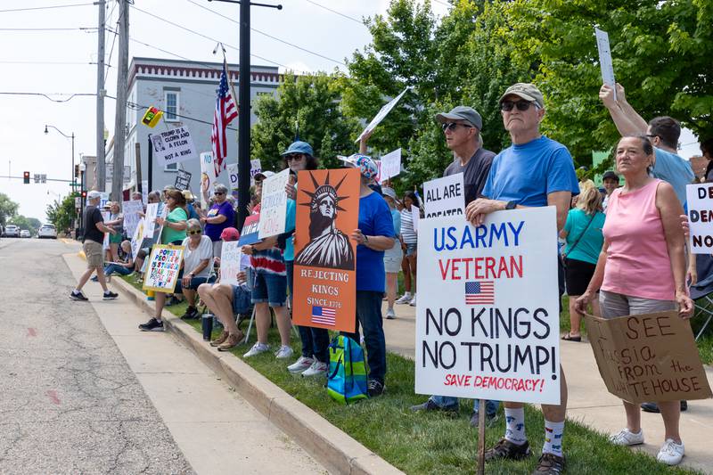 Protesters hold signs at the “No Kings” protest on Saturday, June 14, 2025 at Rotary Park in Princeton.