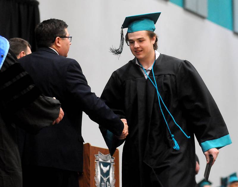 Tyler Long shakes hand with school board members after receiving his diploma Saturday, May 14, 2022, during the graduation ceremony at Woodstock North High School.